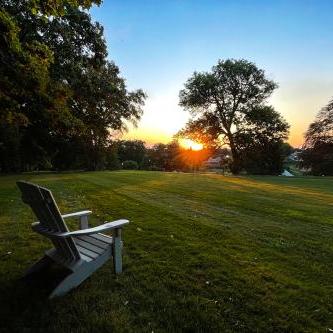 Empty chair in a grass field looking over a sunset. 